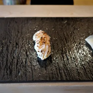 a piece of sushi on a black plate