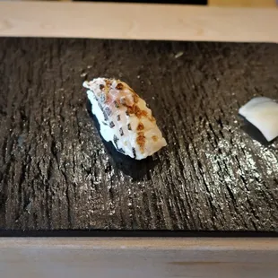 a piece of sushi on a black plate