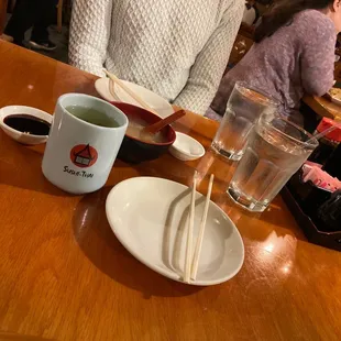 a woman sitting at a table with chopsticks