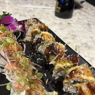 a variety of sushi rolls on a black plate