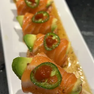 a plate of sushi with avocado and jalapenos