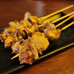 skewered meat on a black plate