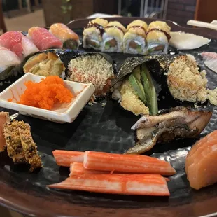 Round One from the top left: Kuchi Special Roll, Golden Roll, hand roll, 2 Piece Tobiko, 2 Piece Eel, peppered salmon, crab, and salmon