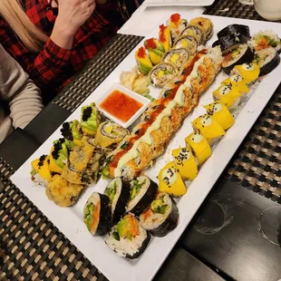 a woman taking a picture of a platter of sushi