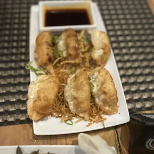 a plate of dumplings and a bowl of sauce