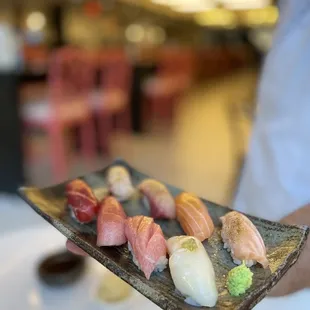 a person holding a plate of sushi