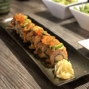 a long roll of sushi on a black plate