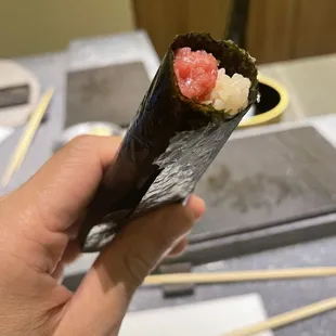 a hand holding a piece of sushi