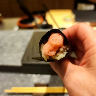 a hand holding a piece of sushi