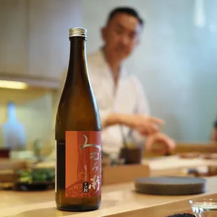 a man sitting at a table with a bottle of sushi