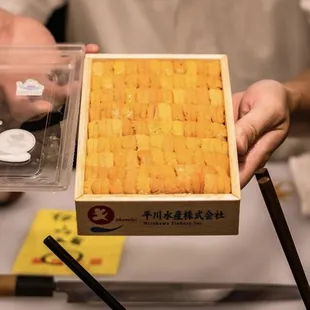 a person holding a box of sushi