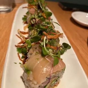 a long white plate with a sushi on it