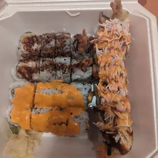 a variety of sushi in a styrofoam container