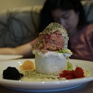a plate of sushi with a woman in the background