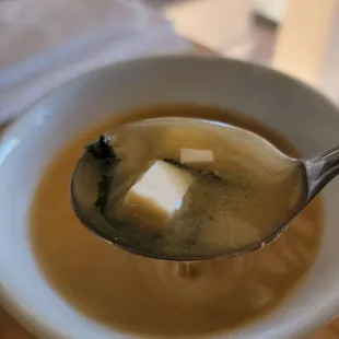 a bowl of soup with a spoon full of soup