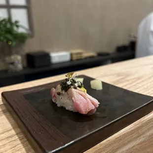a piece of sushi sitting on a black plate