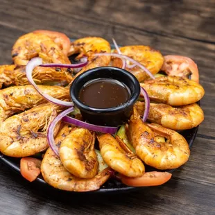 a plate of grilled shrimp with dipping sauce