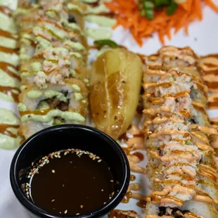 a plate of sushi with sauce and vegetables