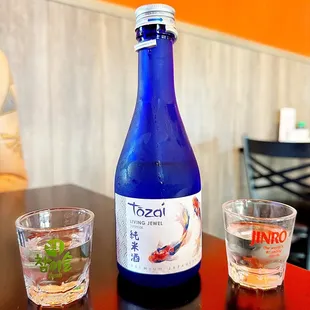 a blue bottle and two shot glasses on a table