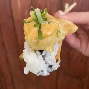  hand holding a piece of sushi