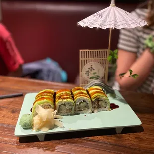 a plate of sushi with a woman in the background