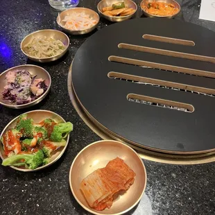 Korean side dishes like kimchi, bean sprouts, fish cakes, pickles carrots and radishes.