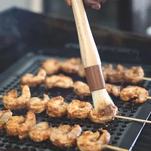 a person using a spatula to stir shrimp on a grill