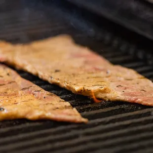 two pieces of meat cooking on a grill