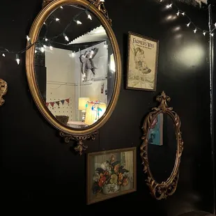 a black wall with a gold frame and mirror