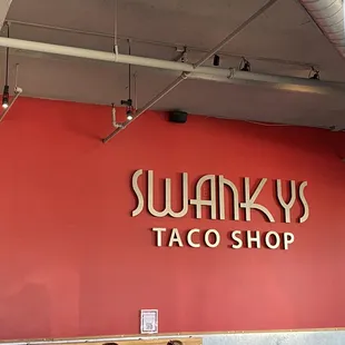 a red wall with a sign that says swanky&apos;s taco shop