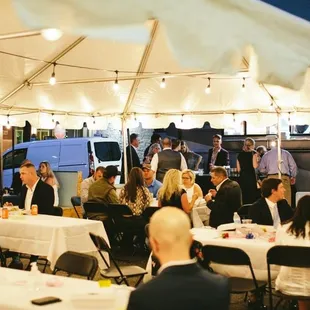 a group of people sitting at tables under a tent
