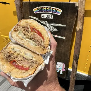 a person holding a sandwich in front of a food truck