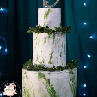 a three - tiered cake decorated with greenery
