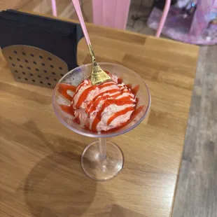 Strawberry Cheesecake Ice cream in a martini glass drizzled with raspberry syrup.