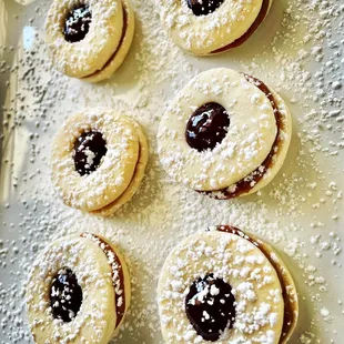 a plate of cookies with jam and powdered sugar
