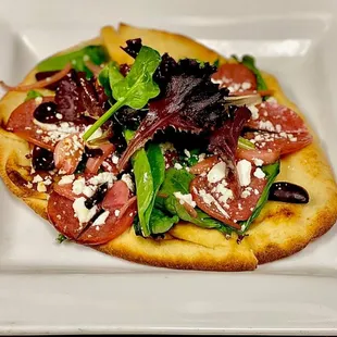 a flatbread pizza topped with fresh greens