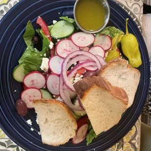 a plate of salad with bread and pickles
