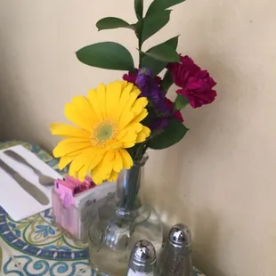 a vase of flowers on a table with salt and pepper shakers