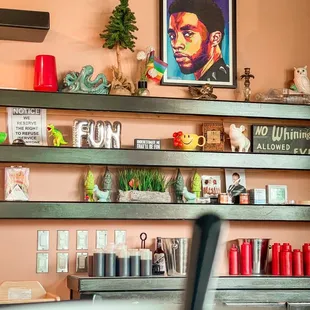 Shelves with art, items, signs and an art piece of Chadwick Boseman!