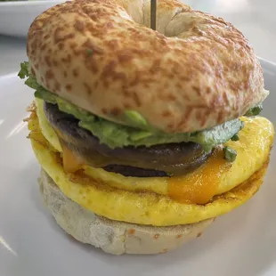 Egg, smashed avocado, impossible sausage cheddar cheese on an Asiago bagel
