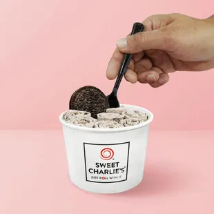 a person scooping a cookie into a cup of ice cream
