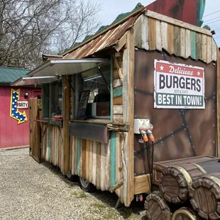 a small wooden building with a sign for burgers best in town