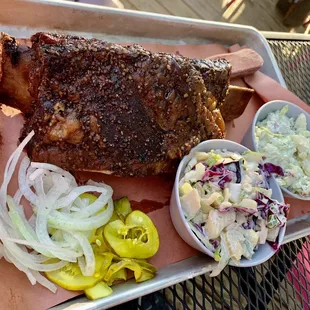 a tray of ribs, coleslaw, and pickles