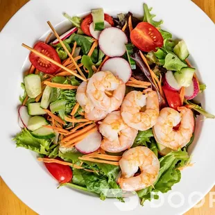 a salad with shrimp, lettuce, tomatoes, cucumbers, and carrots