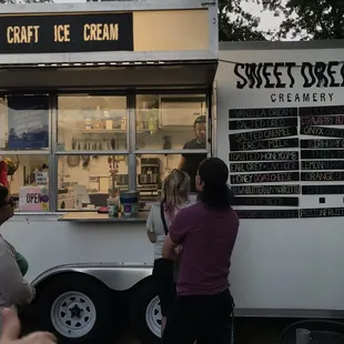 people standing in front of a sweet dream ice cream truck