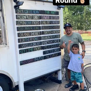 a man and a child standing in front of a food truck