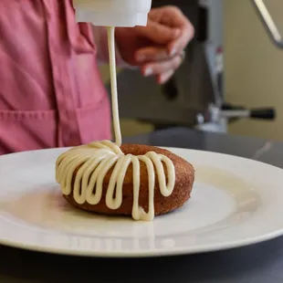a doughnut being drizzled with icing