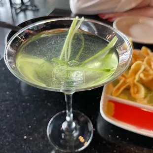 a martini with a green liquid and a side of tortillas