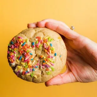 a hand holding a cookie with sprinkles