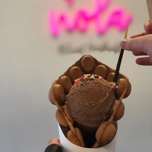 Chocolate bubble waffle with chocolate ice cream with toppings.